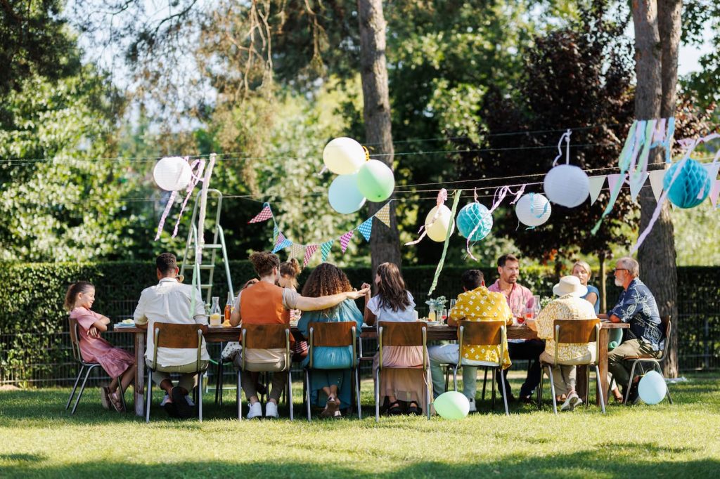 familie und freunde sitzen wahrend einer sommergartenfeier im freien der party tische 1 Dixis f&uuml;r Bayern